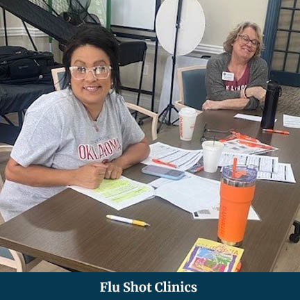 Two women sitting at a check-in table at a flu clinic