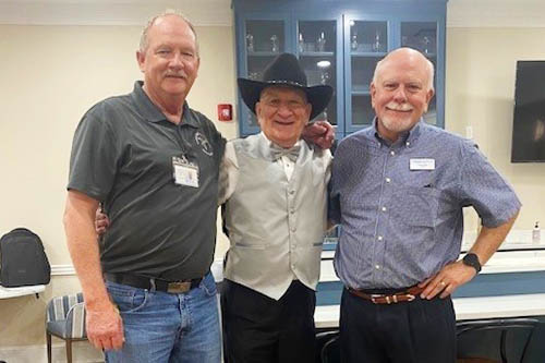 Three men helping with a celebration are standing in side-by-side pose for a picture.