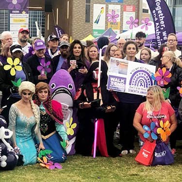 Group of Halloween costumed attendees posing for the camera side-by-side of the Alzheimer's Walk