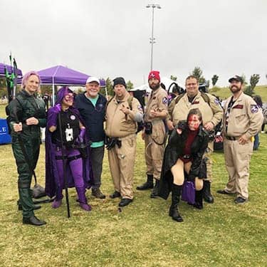 Group of Halloween Ghostbusters costumed attendees posing for the camera side-by-side of the Alzheimer's Walk