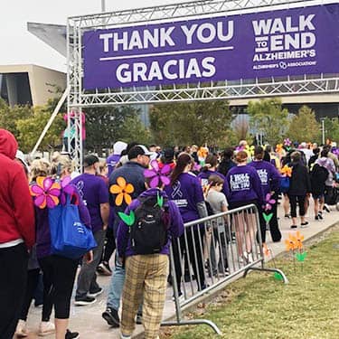 Walking group of attendees walking through the arch at the Alzheimer's Walk