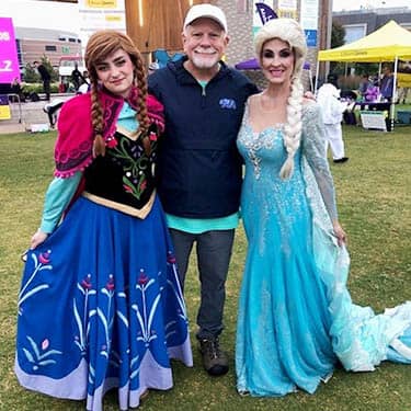 Man posing with a Halloween Princess costumed attendees at the Alzheimer's Walk