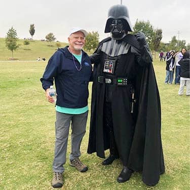 Man posing with a Halloween Darth Vader costumed attendees at the Alzheimer's Walk