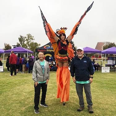 Man posing with a Halloween Butterfly costumed attendees at the Alzheimer's Walk