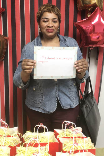 Right at Home West Houston / Sugar Land caregiver holding up a sign about what they love about their job along with popcorn gift bags in the front