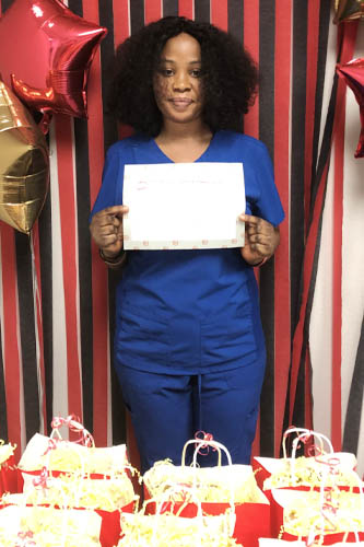 Right at Home West Houston and Sugar Land caregiver holding up a sign about what she loves about her job along with popcorn gift bags in the front