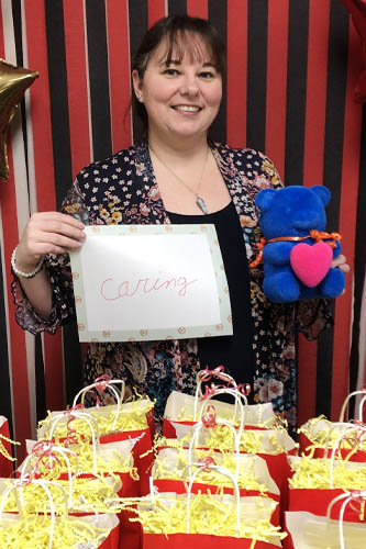 Right at Home West Houston and Sugar Land caregiver holding up a sign about what she loves about her job along with popcorn gift bags in the foreground