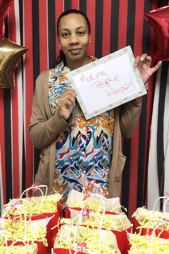 Right at Home West Houston & Sugar Land caregiver holding up a sign about what she loves about her job along with popcorn gift bags in the foreground