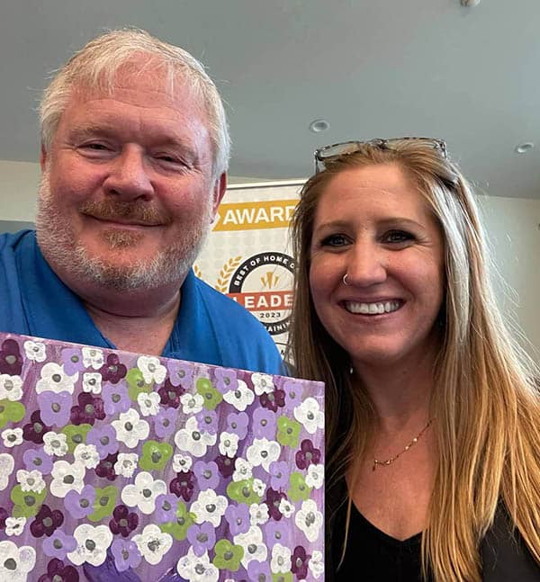 Jim Gall and wife hold paintings 