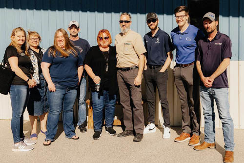 Camp Hope Veteran's Care program team of nine men and women standing side-by-side posing for the camera