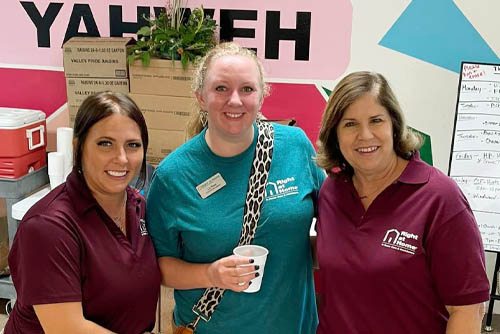 Three Mission of Yahweh faith-based female shelter volunteers standing side-by-side and smiling at the camera