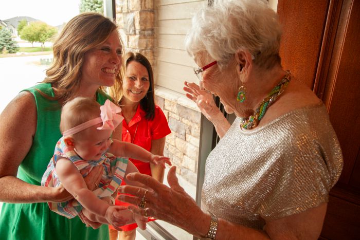 senior woman greeting two younger women and a baby