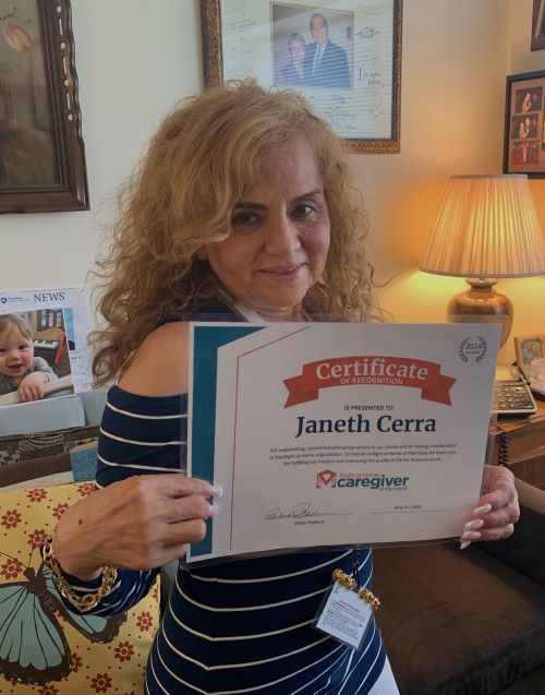 Janeth standing with her Caregiver of the Month Award