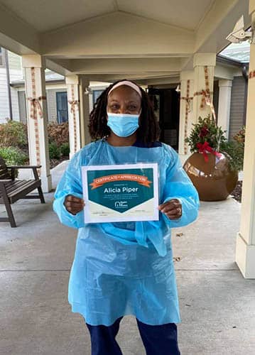 Alicia Piper holding her Caregiver of the Month Award certificate for November of 2020