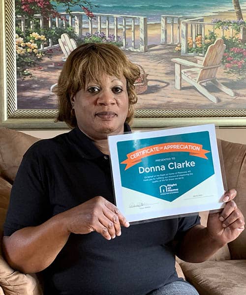 Donna Clarke holding her Caregiver of the Month Award certificate for May of 2021