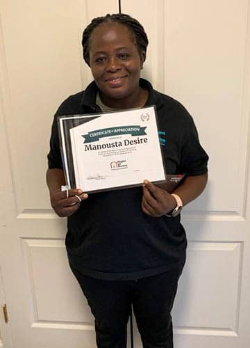 Manousta Desire holding her Caregiver of the Month Award certificate for October 2021