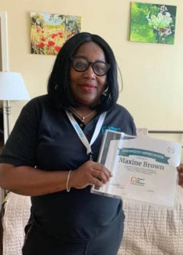 Maxine Brown holding her Caregiver of the Month Award certificate for September 2021