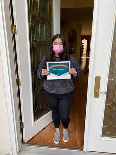 Sandra Guardado holding her Caregiver of the Month Award certificate for December of 2020