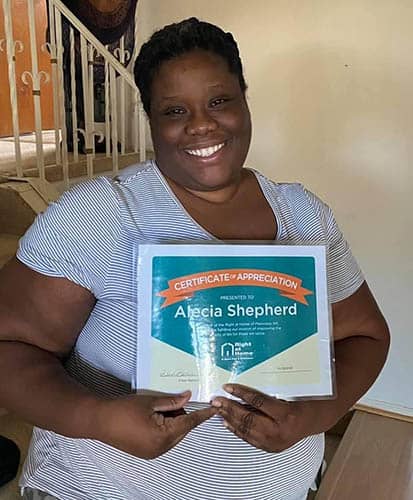 Alecia Shepherd holding her Caregiver of the Month Award certificate for January of 2021