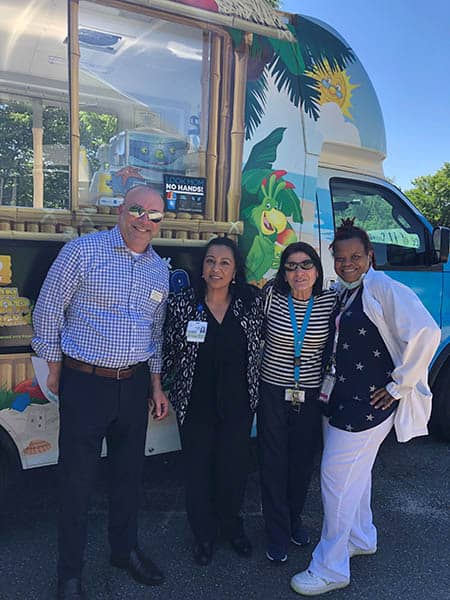 Gregg Balbera and three staff members of Huntington Hills Rehab Center in front of the Kona Ice truck