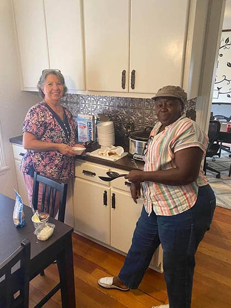 Two female staff members of the Right at Home Brenham, TX team hanging out in the kitchen of the Right at Home Brenham office.