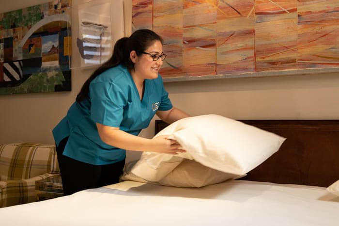 Right at Home Smithtown, NY female caregiver preparing a bed for senior client