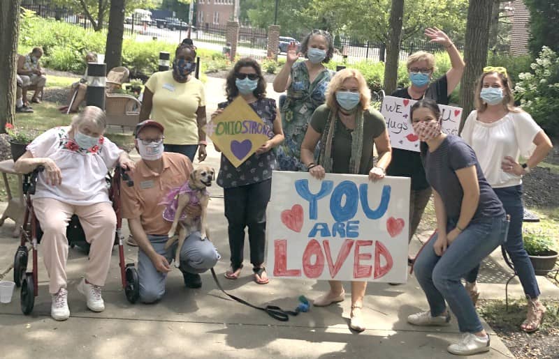 Group of people in face masks with signs including one that says You are Loved