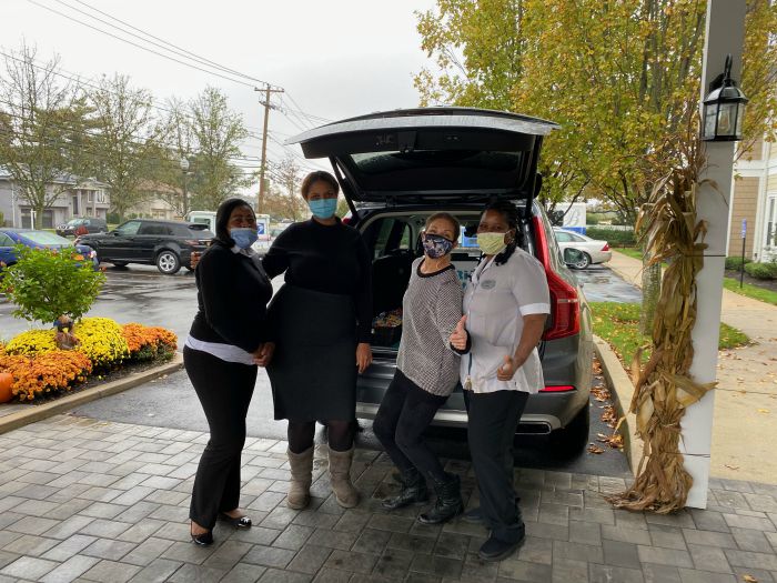 Right at Home South Shore Long Island delivering refreshments to front line workers at the Bristal North Woodmere assisted living communities with a “snackmobile”. Four females standing behind Right at Home vehicle with snacks in the back.