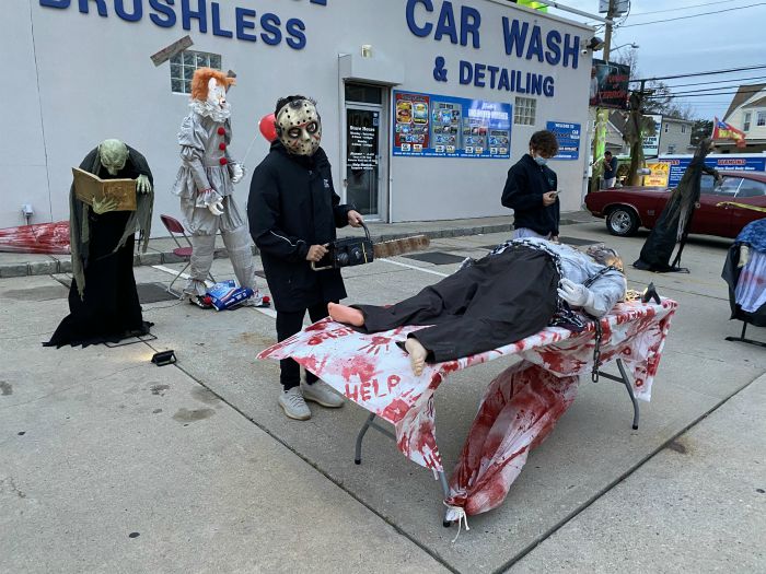 Right at Home volunteering at the Kids Need More Haunted Car Wash at Johnnies Car Wash in Copiague, NY. Two volunteers standing next to scary attractions lining the way into the car wash