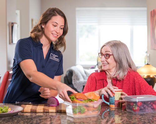 Female Caregiver Helping Female Senior With Meal Preparation