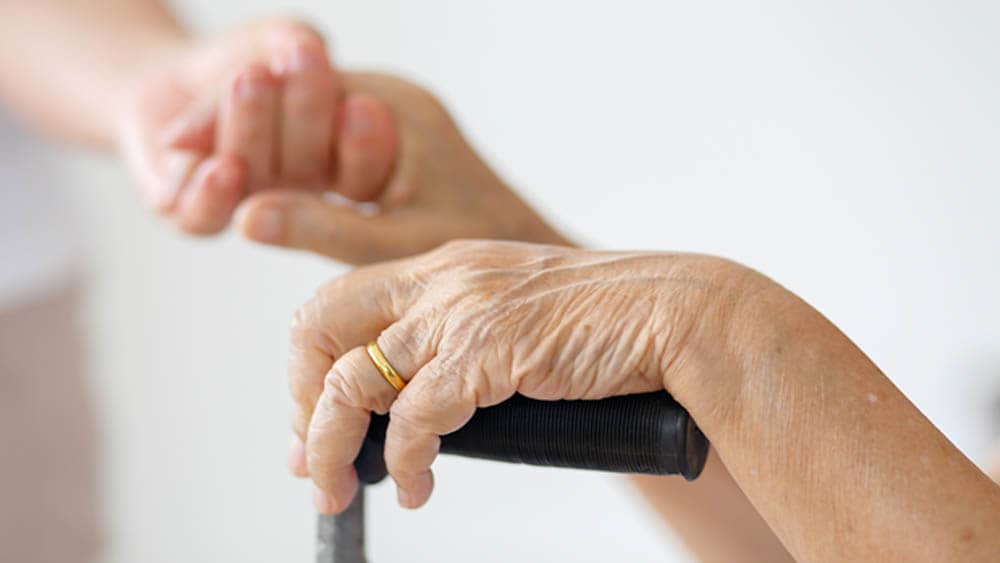 Senior Hands with A Wedding Ring Holding Hands With A Younger Woman