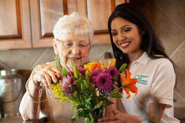 Caregiver helping female client arrange flowers