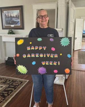 Caregiver Anna Fletcher Holding a "Happy Caregiver Week" sign