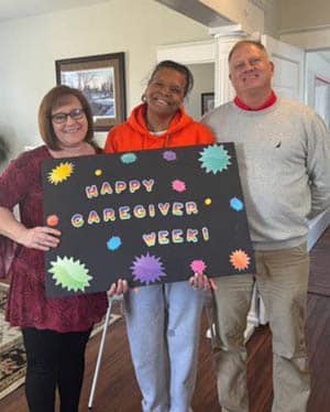 Caregiver Cella Baker standing with Debbie Smith and Pete Lawrence