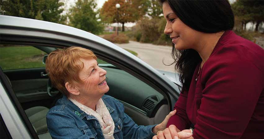 A Milwaukee, Wisconsin female caregiver helping a female client get out of a car.