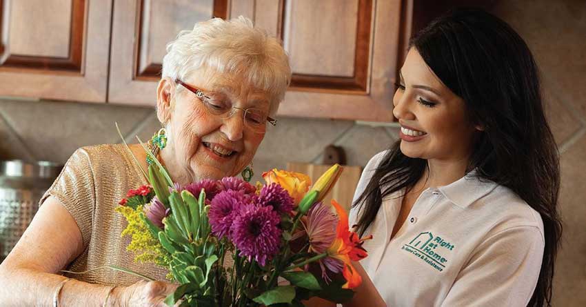 A Shorewood, Wisconsin female caregiver holding a bouquet of flowers with a female client.