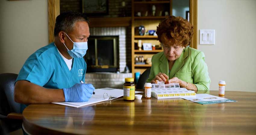 A Milwaukee, Wisconsin male caregiver helping a female client with their medications.