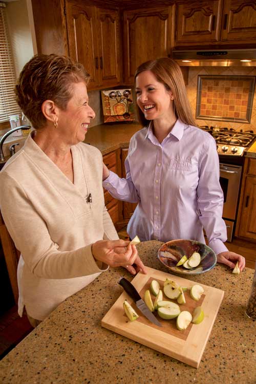 Caregiver and Senior cutting apples