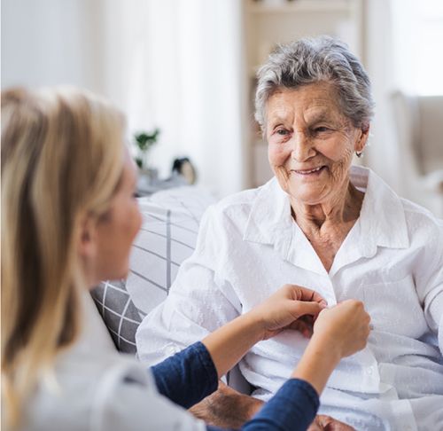 caregiver helping senior button up shirt