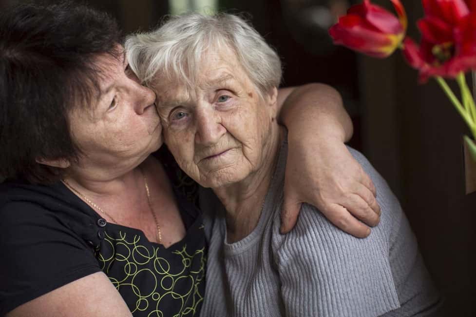 daughter kissing elderly mother