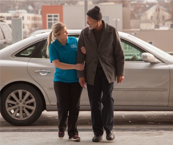 Caregiver helping senior client out of car and into appointment