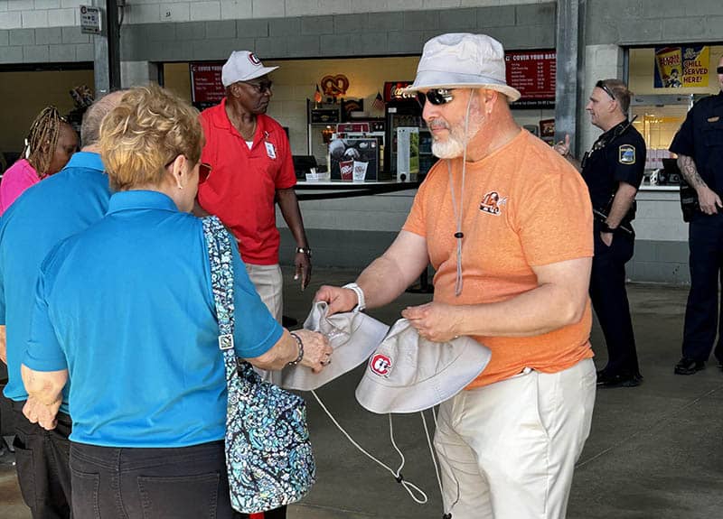 Handing out hats to senior baseball fans