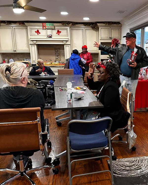 Several people sitting at a table. Others are standing or getting food.