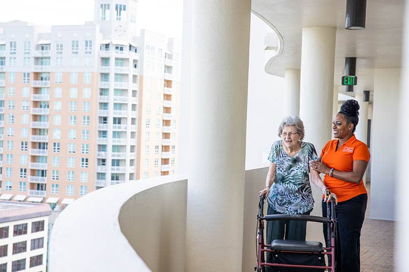 Caregiver and senior client on apartment balcony