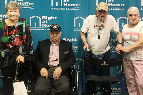 Group photo of two women and two men seated and standing at a Holocaust Survivors and Veterans Gathering