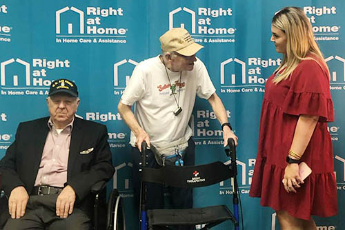 Group photo of two men and a woman seated and standing at a Holocaust Survivors and Veterans Gathering