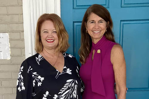 Two Women Pose for a Photo in Front of a Blue Door at an Open House in Lafayette