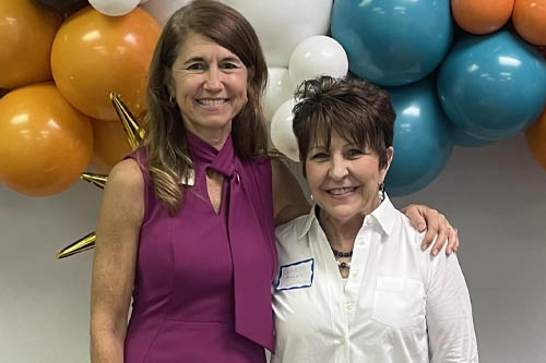 Two Women Pose for a Photo in Front of Balloons at an Open House in Lafayette