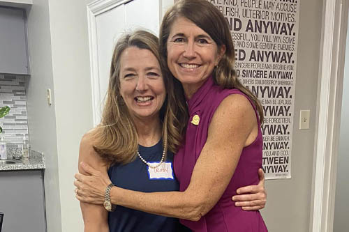 Two Women Pose in a Hug for a Photo at an Open House in Lafayette