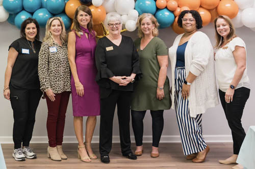 Seven Women Pose for a Photo in Front of Balloons at an Open House in Lafayette